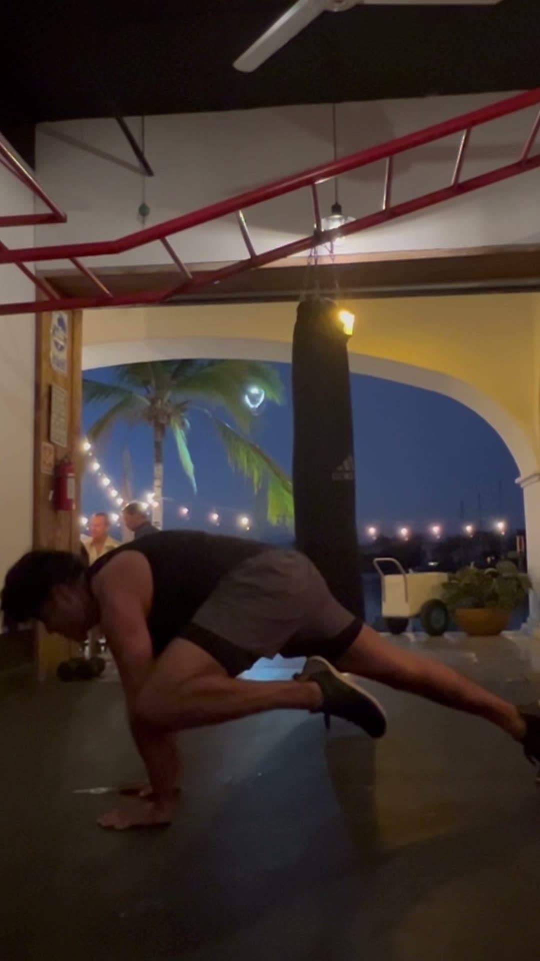 Peak position with the knee tucked and leg extended in a studio at night